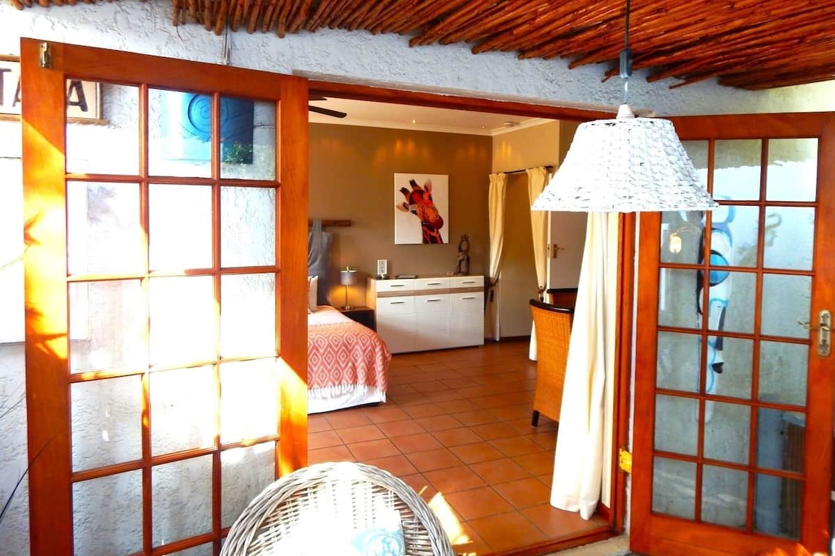 A room with a bed, a desk, a chair, and a fan.