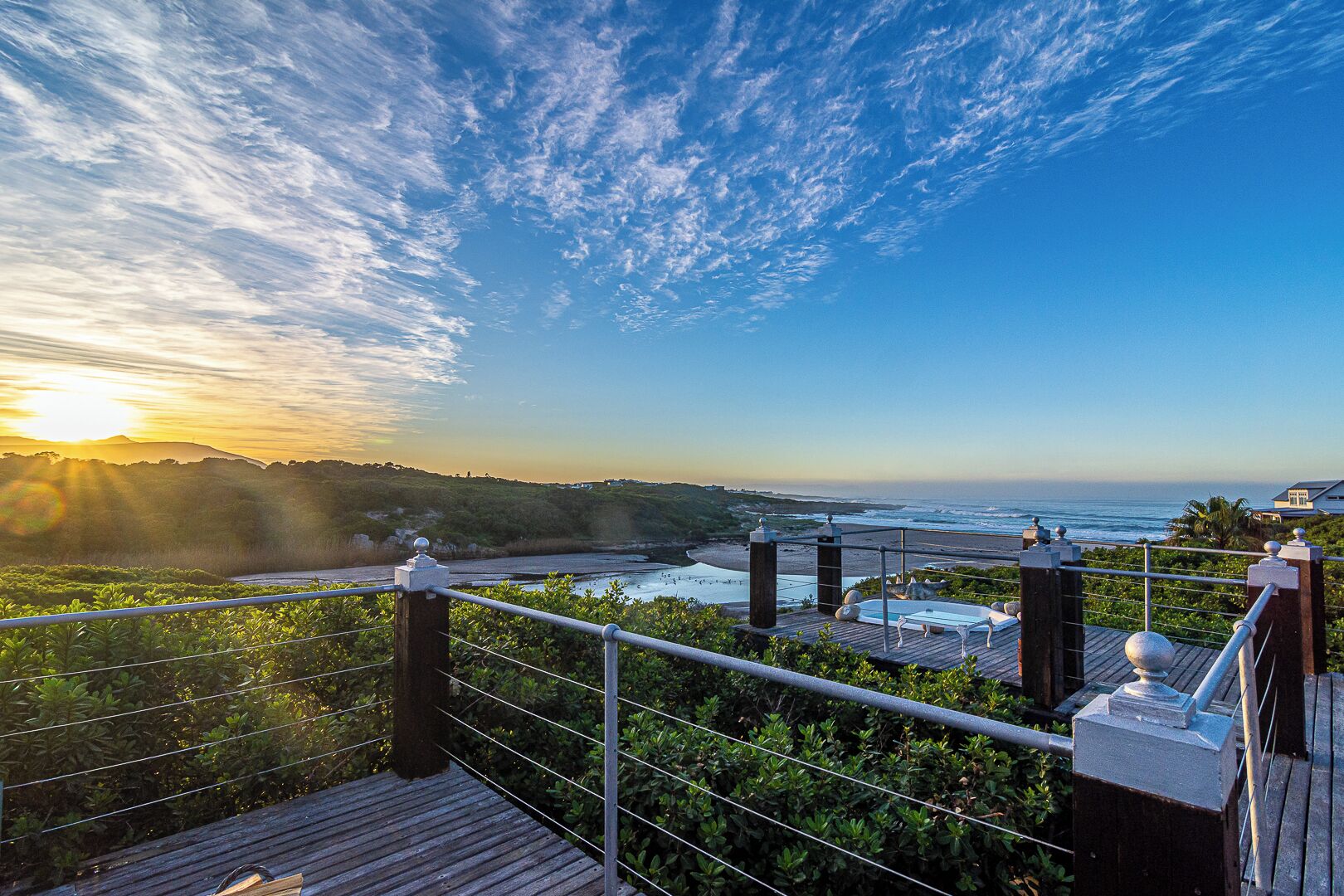 A wooden deck with a view of the ocean and a sunset.