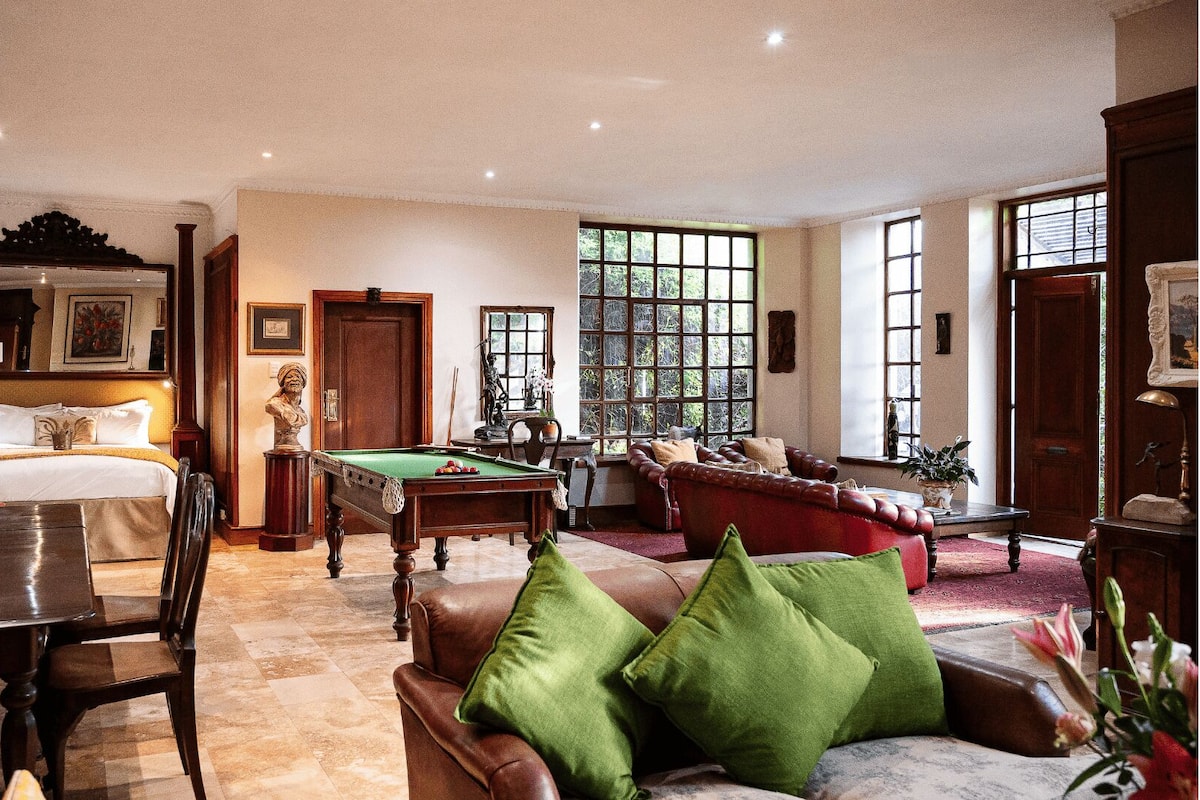 Una habitación bien amueblada con mesa de billar, sofá y cama.