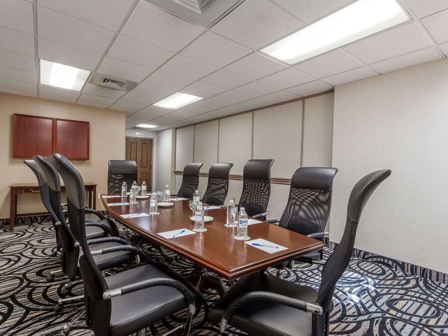 A conference room with a long table, black chairs, and water bottles.