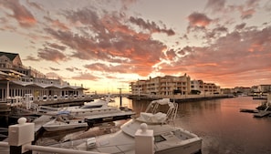 A marina with boats docked, a bridge, and buildings with balconies. - Krystal Beach Hotel (Cape Town)