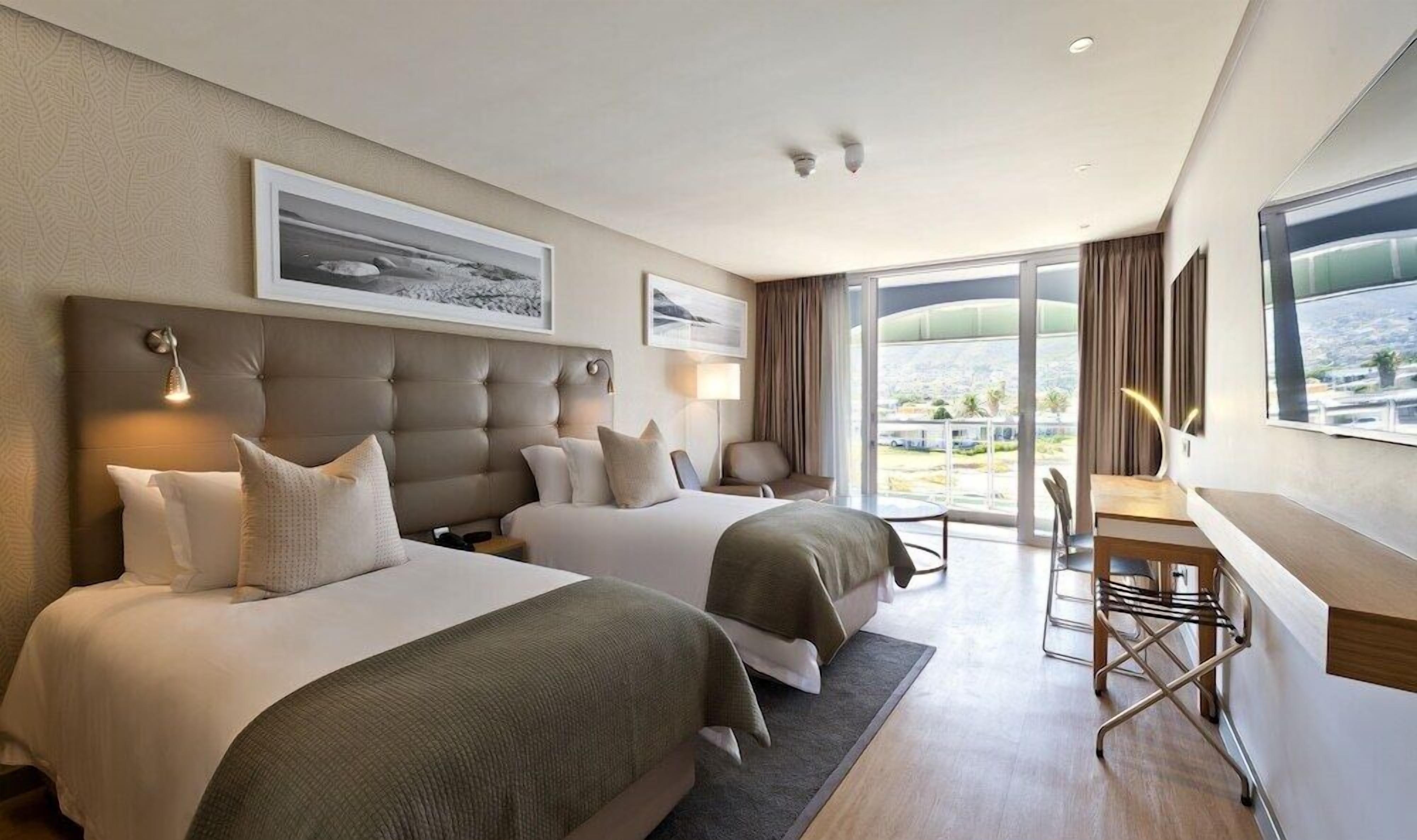 Ett hotellrum med två sängar, ett skrivbord och utsikt över stadsbilden.