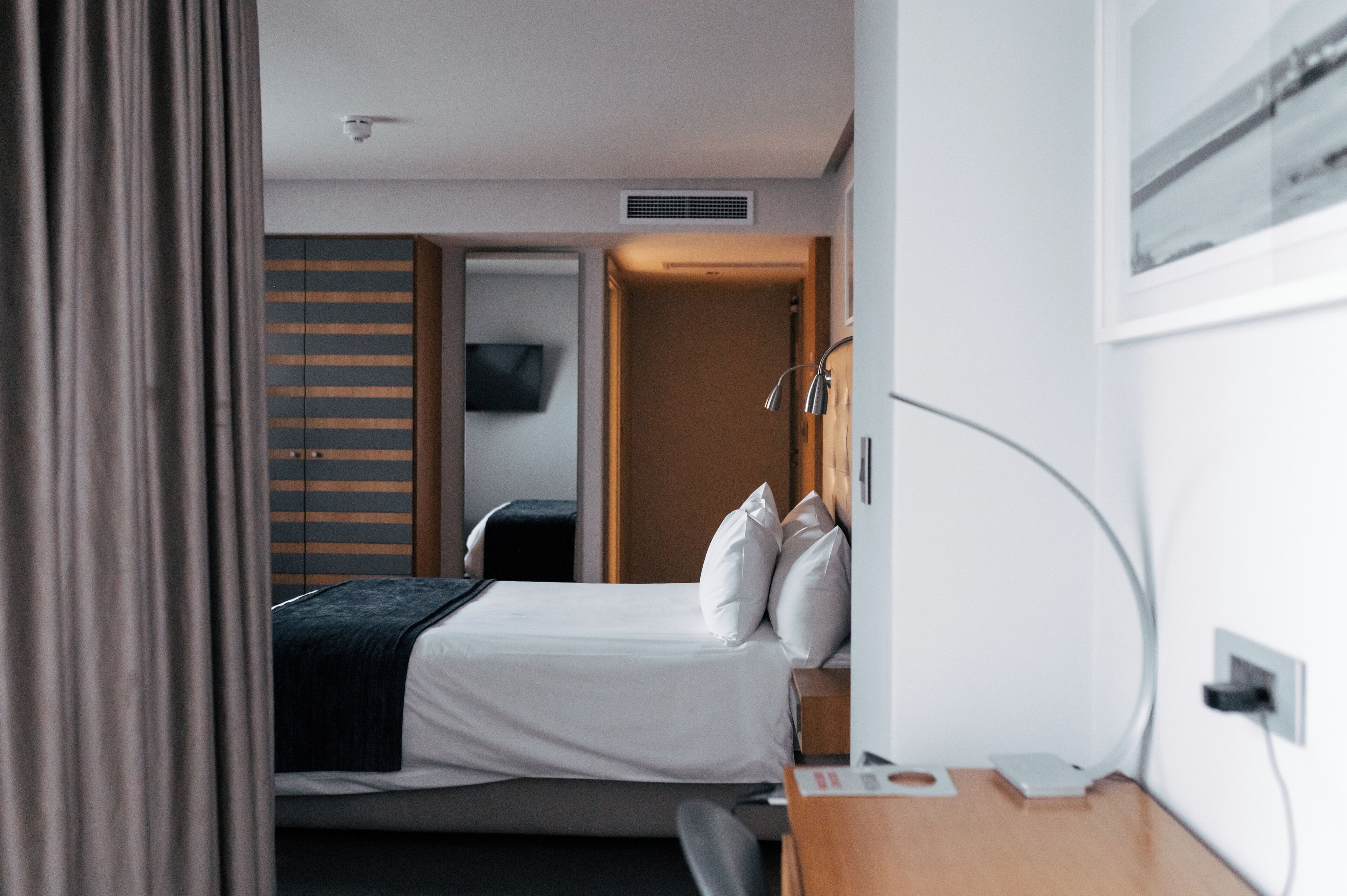 A hotel room with a bed, a desk, a television, and a wardrobe.
