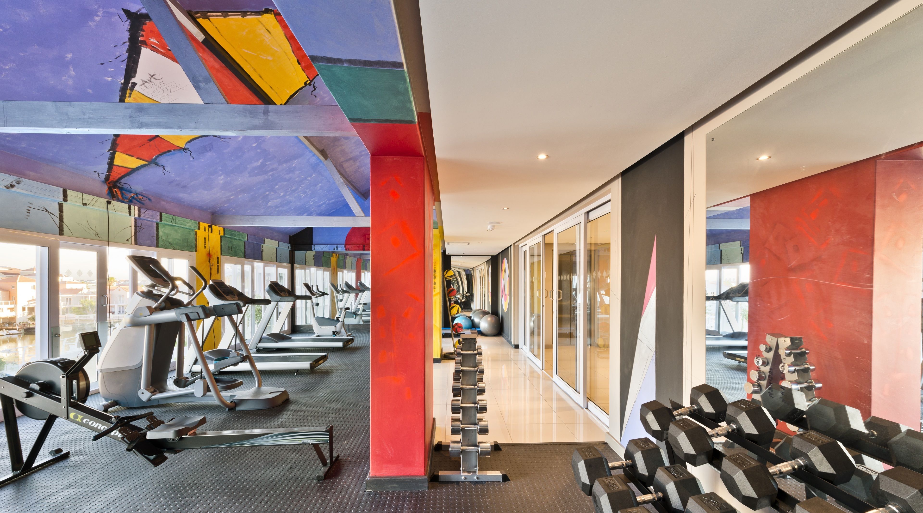 A modern gym with treadmills, weight machines, and free weights.