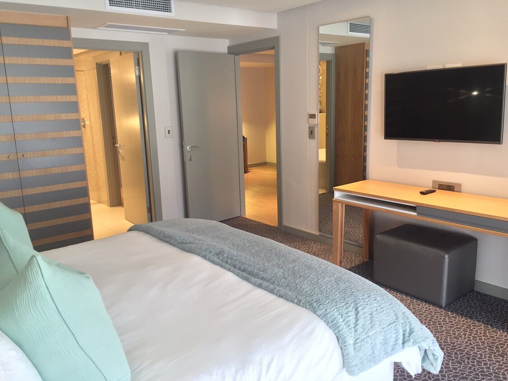 Een hotelkamer met een bed, een bureau, een televisie en een spiegel.