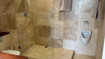 Un baño moderno con ducha de vidrio, suelo de mármol, lavabo empotrado y retrete.