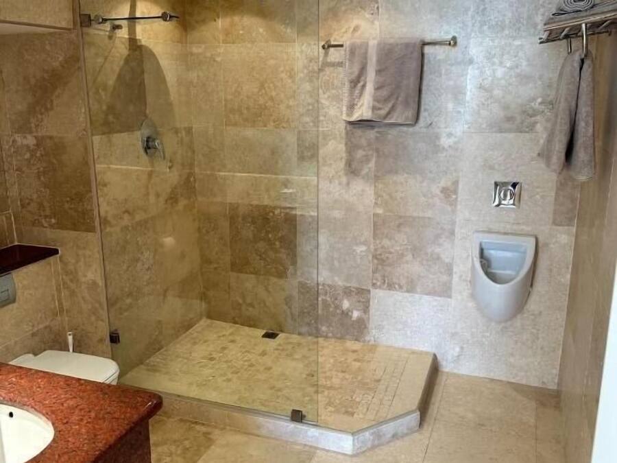 Un baño moderno con ducha de vidrio, suelo de mármol, lavabo empotrado y retrete.