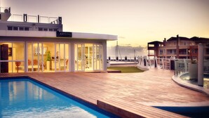 A modern hotel with a pool area, a restaurant, and a view of the sea. - Krystal Beach Hotel (Cape Town)