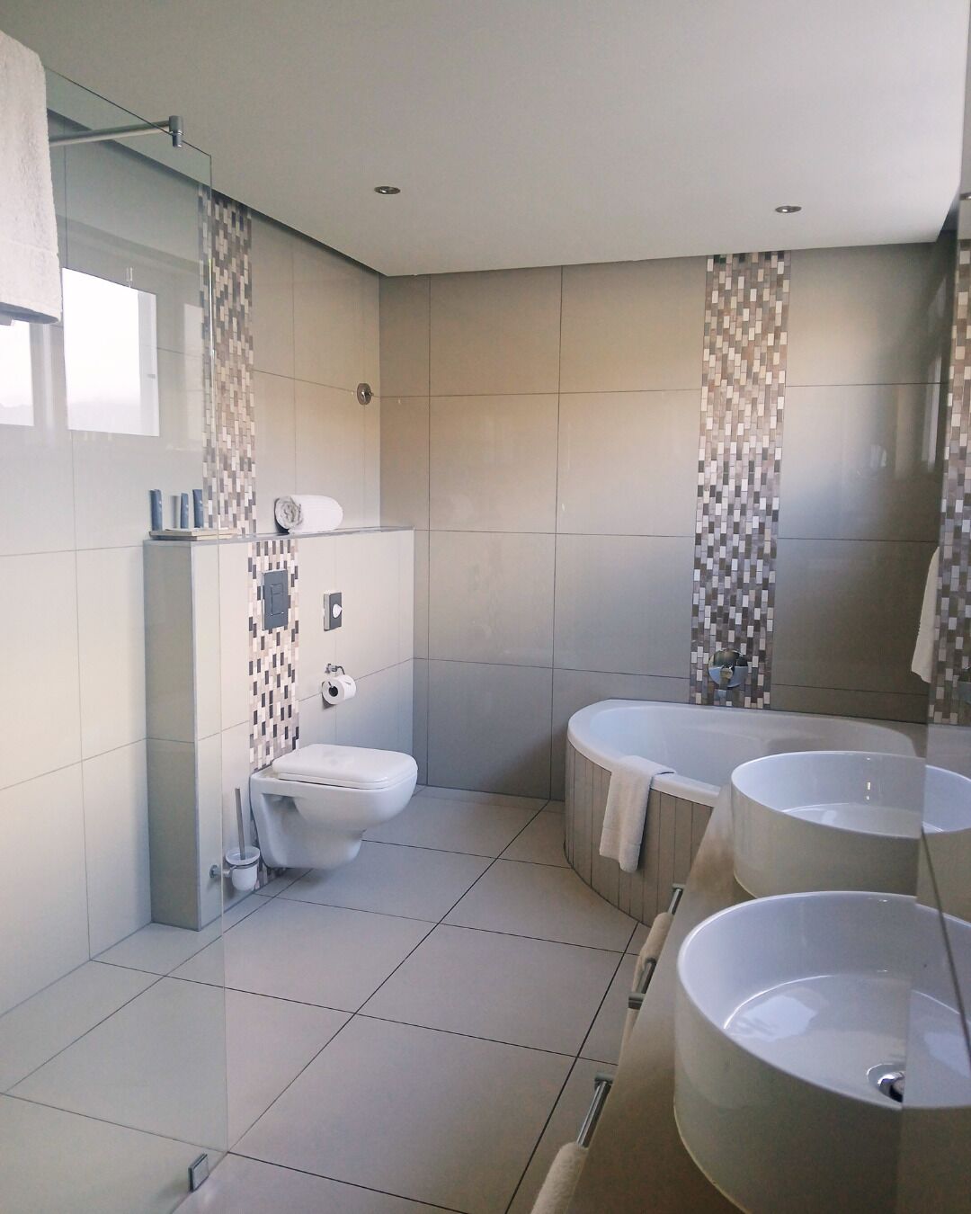 A modern bathroom with a toilet, two sinks, and a bathtub.