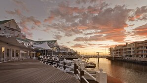 A waterfront hotel with a wooden deck, outdoor seating, and a marina with boats. - Krystal Beach Hotel (Cape Town)