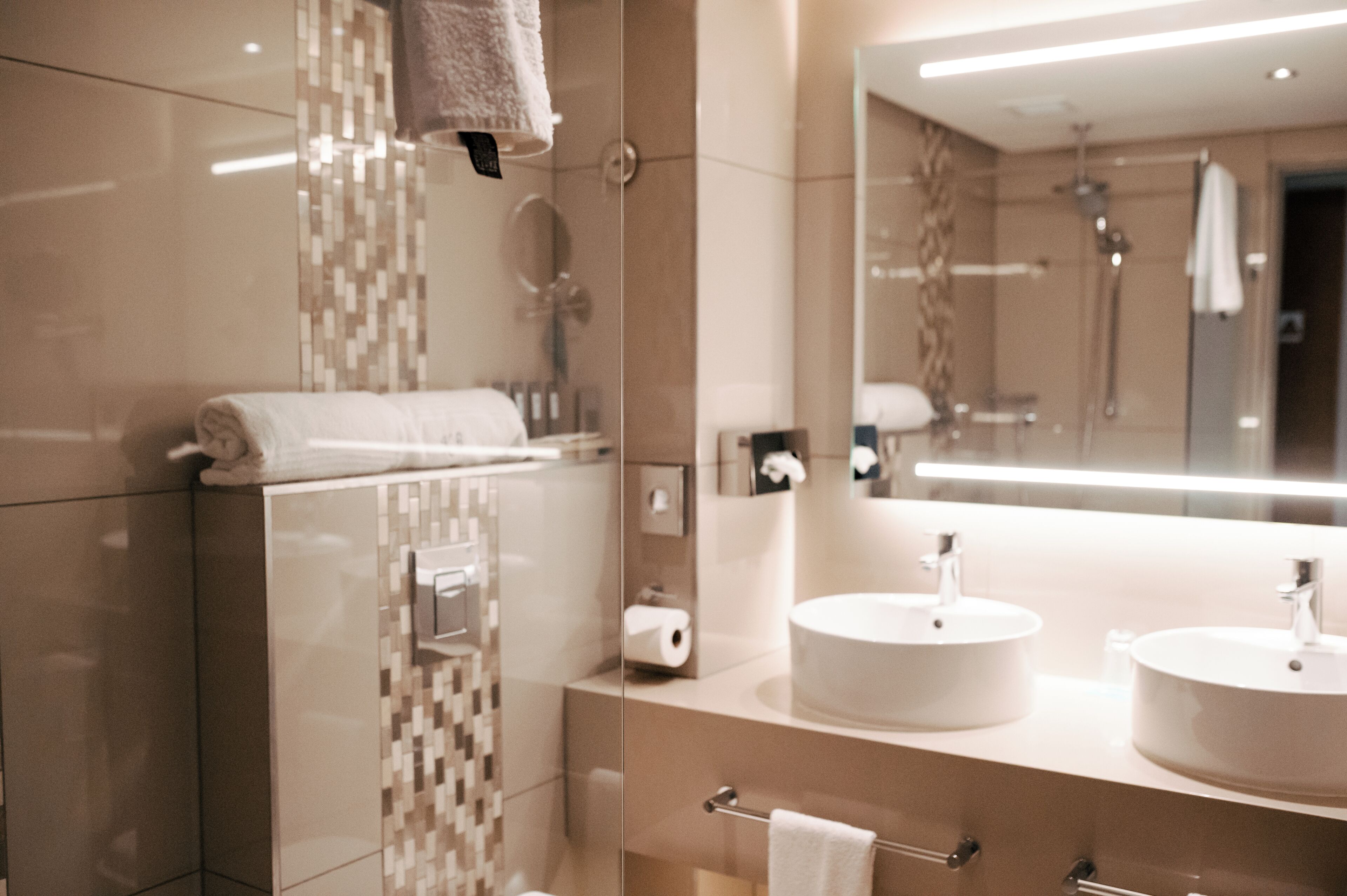 Een moderne badkamer met twee wastafels, een grote spiegel en een douchehoek.