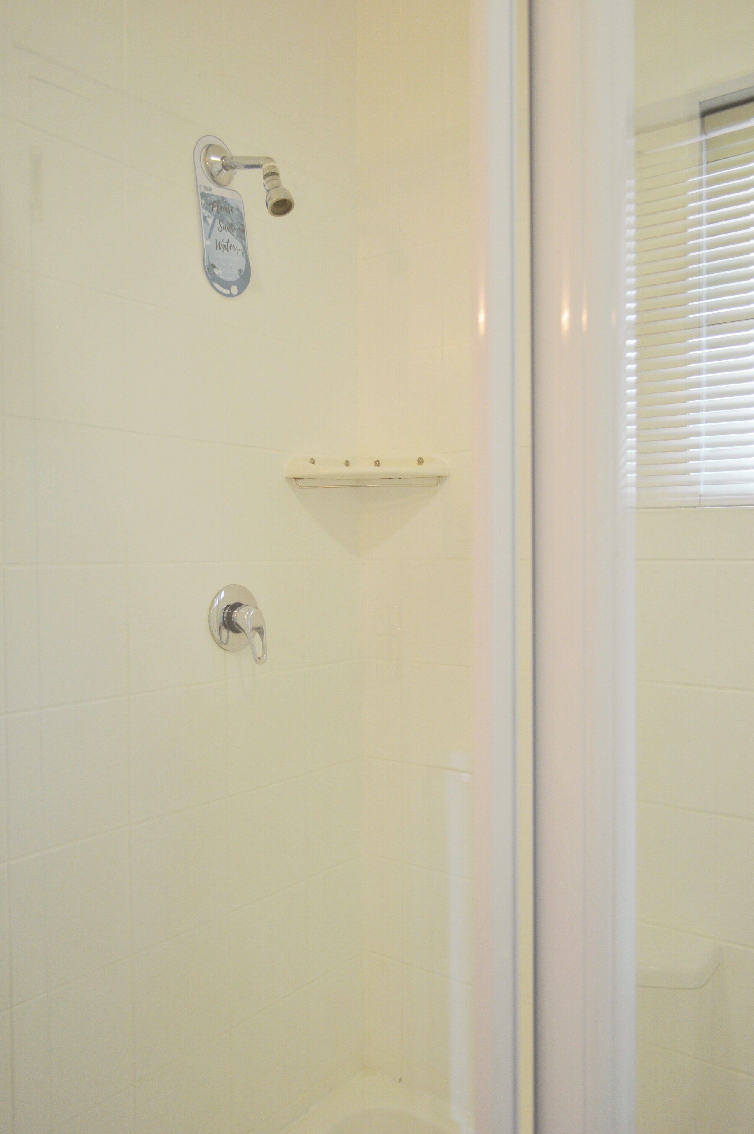 A bathroom with a shower, a toilet, and a towel rack.