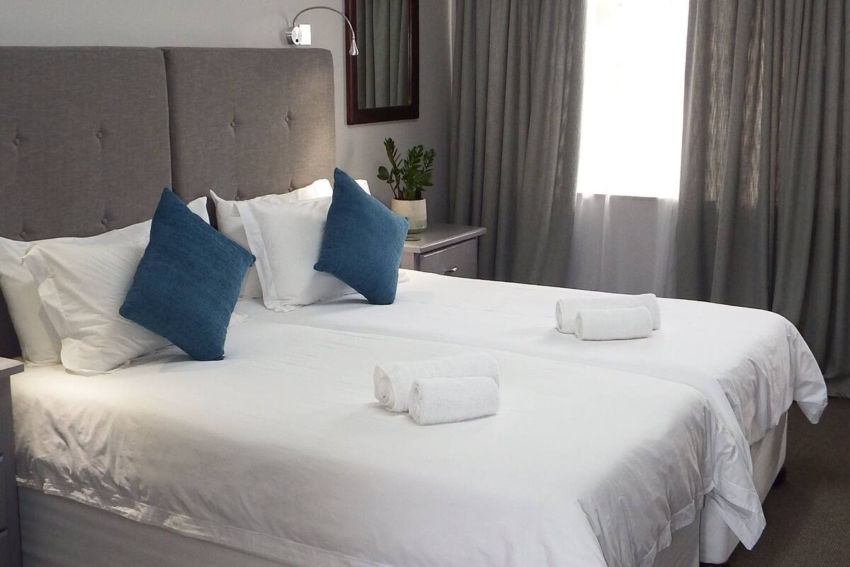 A hotel room with a large bed, a nightstand, a lamp, and a window with curtains.