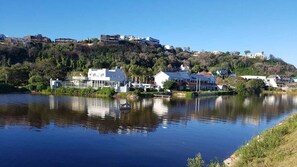 Propiedad junto al lago con edificios blancos, un muelle y una colina con estructuras adicionales.