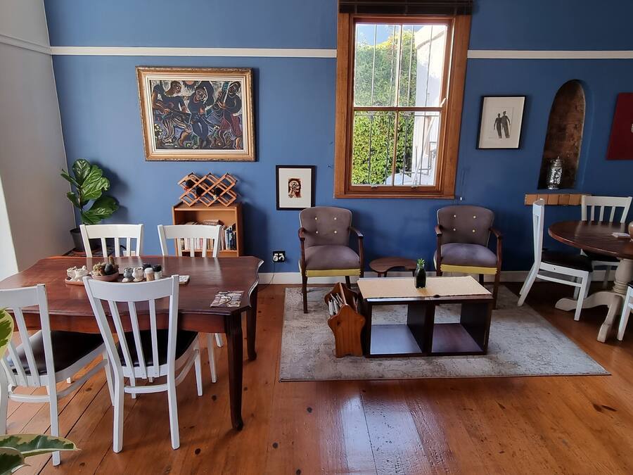 A dining area with a wooden table and chairs, a bookshelf, and a window with a view of greenery.