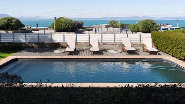 Un espace piscine avec des chaises longues et vue sur la mer.