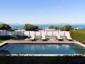 Zona de piscina con sillones y vistas al mar.