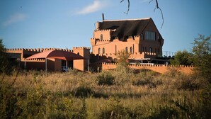 Un grand bâtiment imposant, qui ressemble à un château, avec de nombreuses tours et une structure à toit rouge au premier plan.
