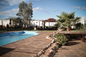 Una piscina al aire libre, sillones reclinables de piscina