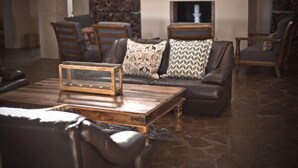 Un salon chaleureux avec un canapé en cuir, une table basse en bois et des coussins à motifs.