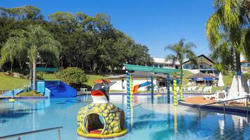 Relax by the pool surrounded by lounge chairs and umbrellas, with a fish-shaped slide and tunnel play area for kids.