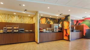 A modern breakfast area with wooden counters, a coffee machine, and a fruit display. - Fairfield Inn & Suites by Marriott Alexandria (Alexandria)