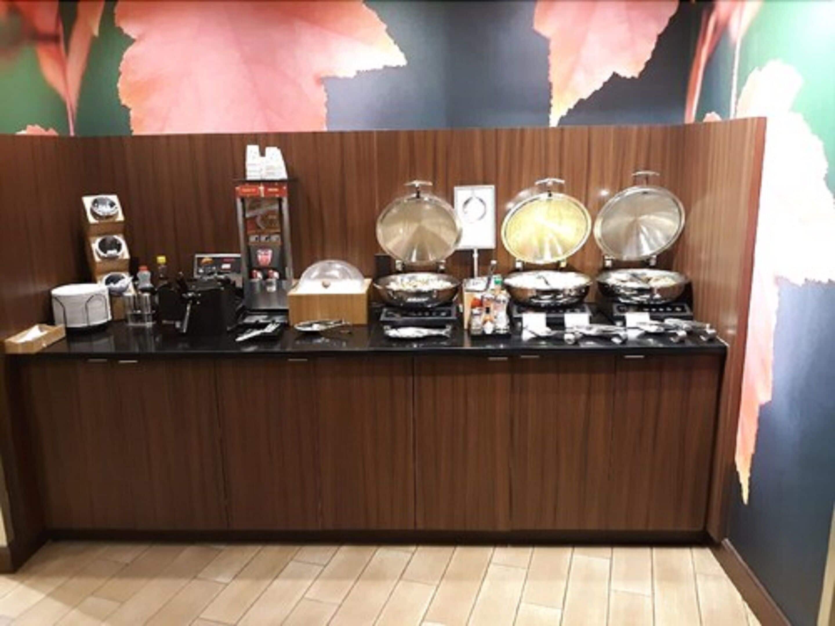 Eine Küchenarbeitsplatte mit verschiedenen Kochutensilien und Geräten, darunter eine Kaffeemaschine, ein Reiskocher und ein Wok.