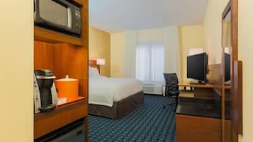 A hotel room with a bed, a desk with a computer, a microwave, and a coffee maker.