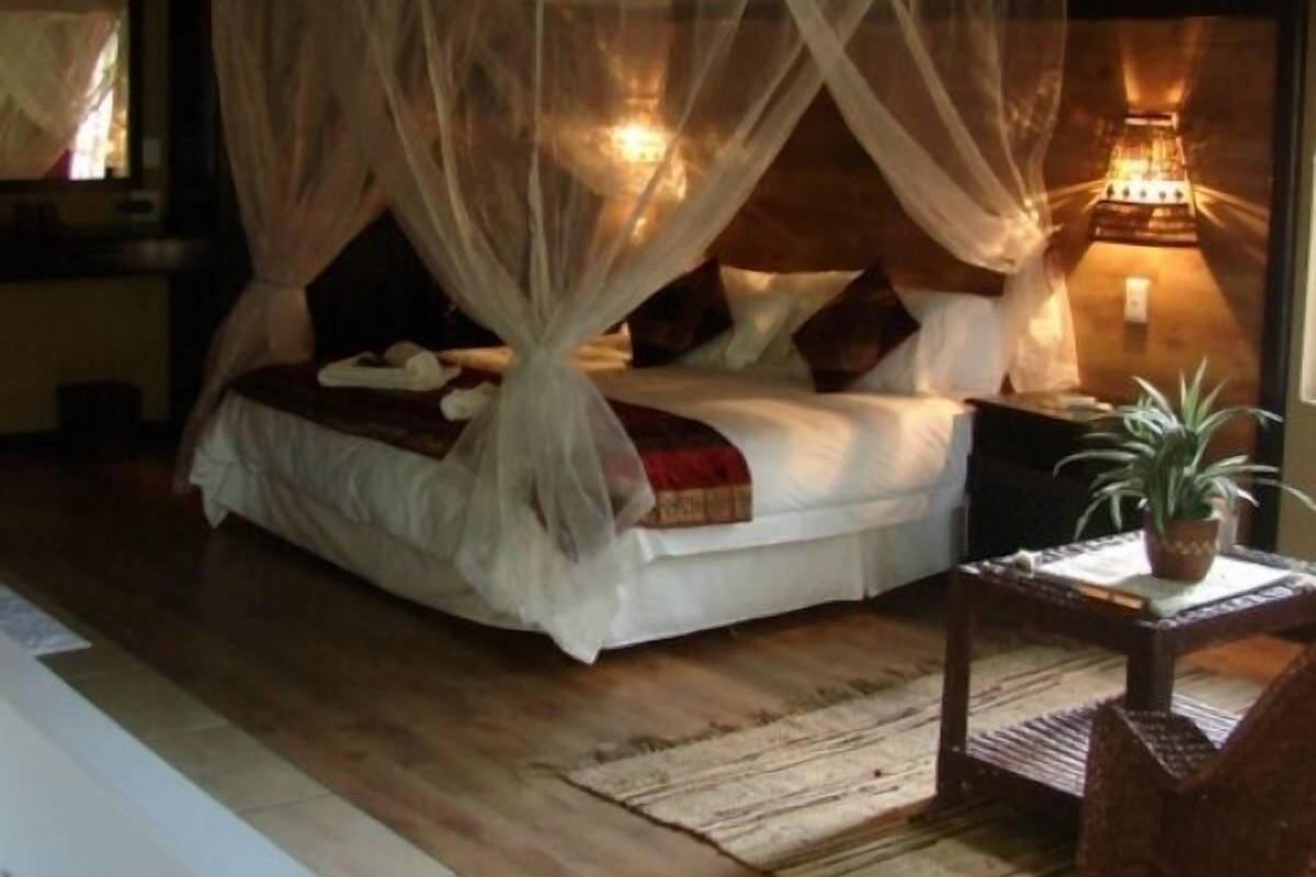 Een slaapkamer met een hemelbed, een nachtkastje met een lamp, en uitzicht op het interieur van de kamer.