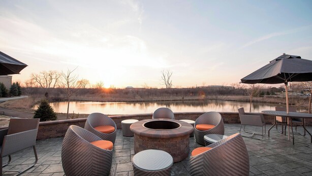 Un espace extérieur aménagé avec des chaises en osier et une table ronde, offrant une vue sur une étendue d’eau.