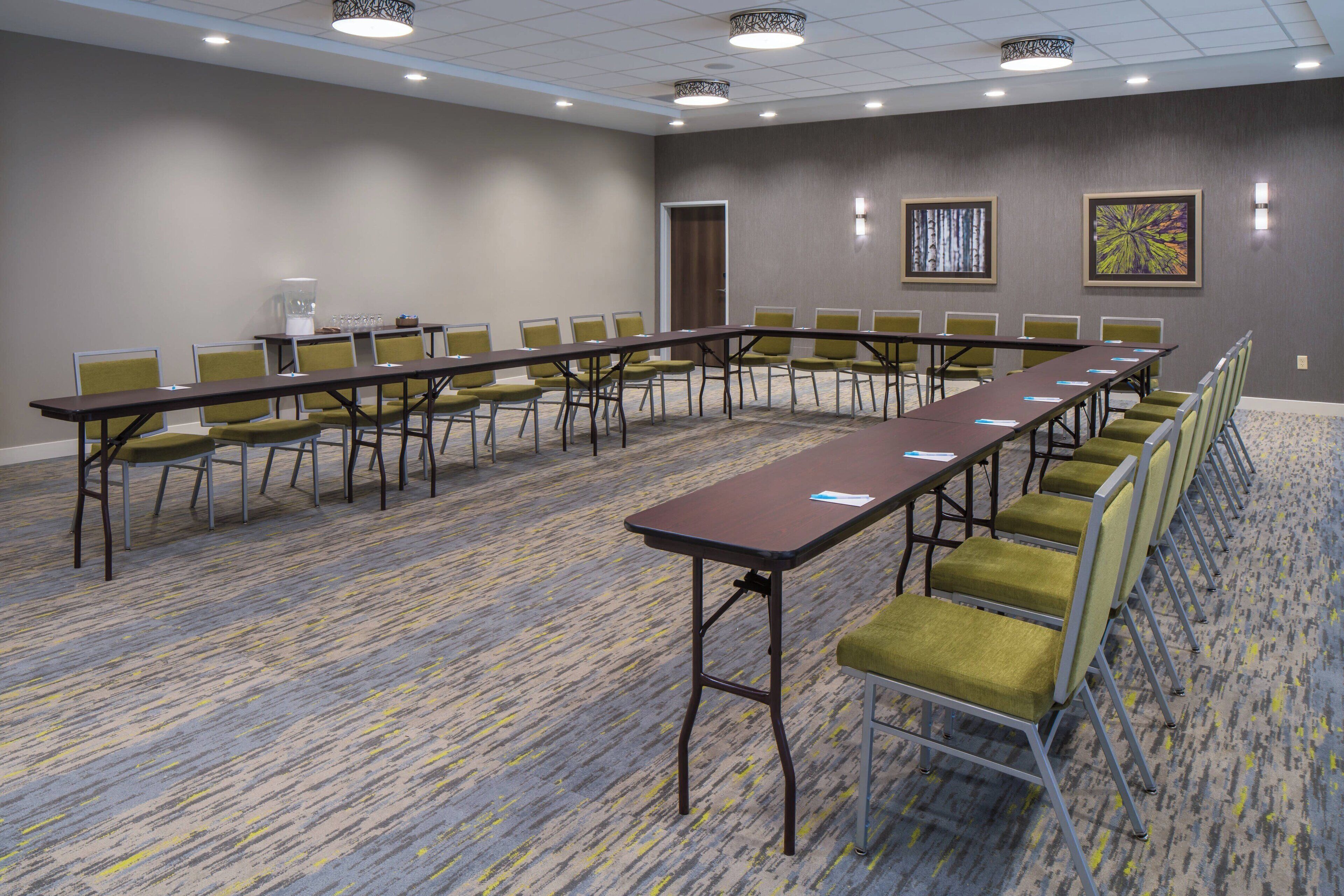 A conference room with a long table and chairs, carpeted floor, and two framed artworks on the wall.