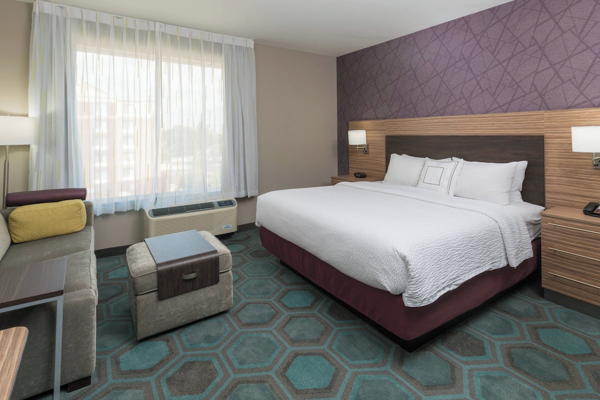 Une chambre d’hôtel avec un grand lit, un canapé, une petite table et une valise.
