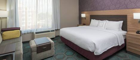 Una habitación de hotel con una cama grande, un sofá, una mesita y una maleta.