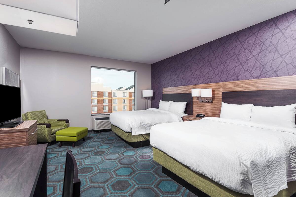 Une chambre d’hôtel avec deux lits, un bureau, une télévision et une fenêtre donnant sur la ville.