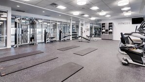 Une salle de sport moderne équipée de divers appareils d’exercice, notamment des tapis de course, des appareils de musculation et des poids libres.
