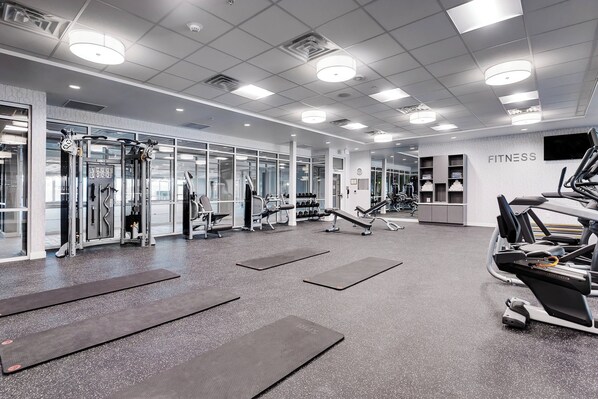 Un gimnasio moderno con diverso equipo de ejercicio, incluyendo cintas de correr, máquinas de pesas y pesas libres.