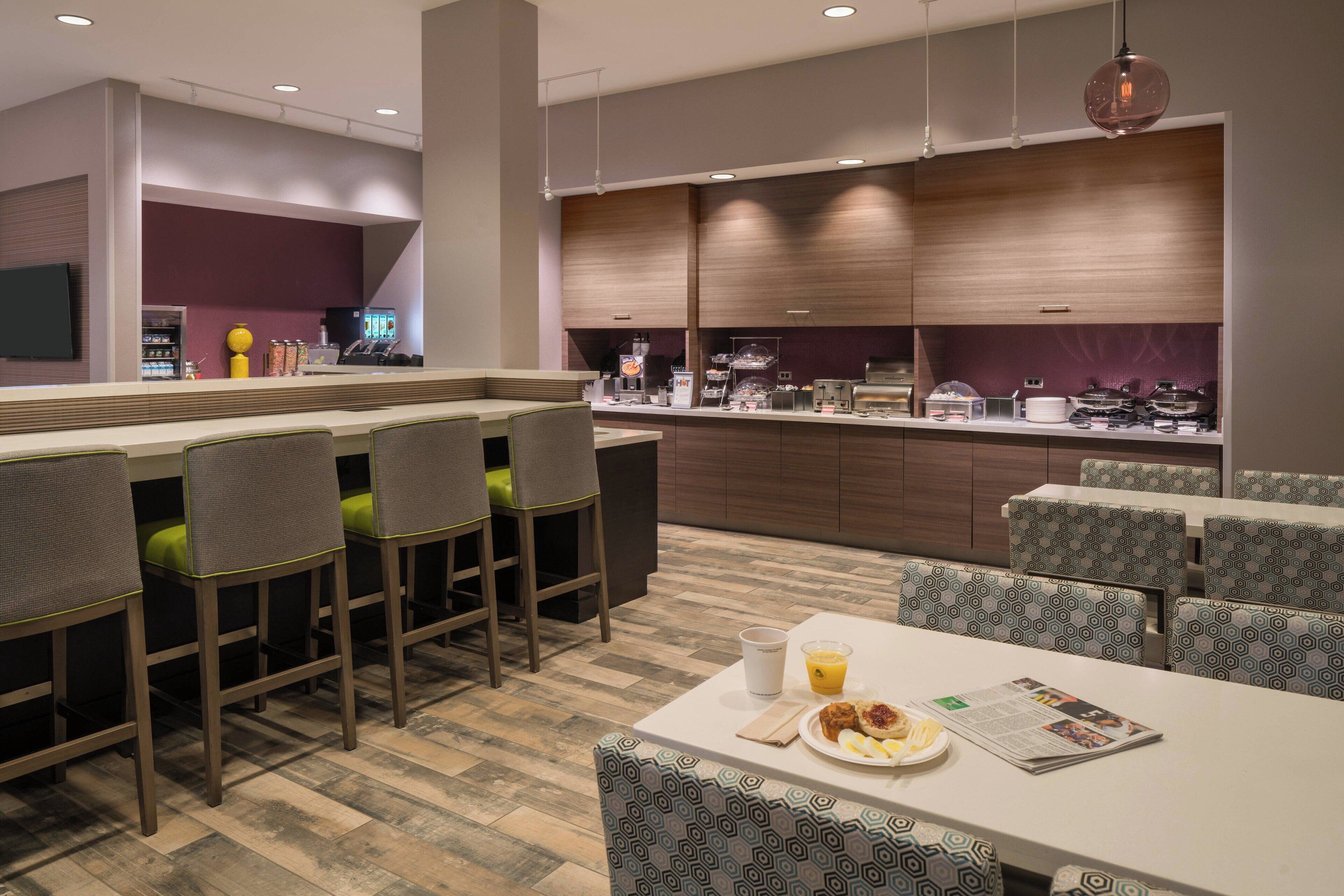 A modern hotel lobby with a bar area, seating, and a counter with food and drink options.