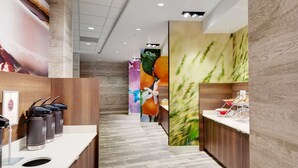 Un hall d’hôtel moderne avec des panneaux de bois, un couloir central et une fresque colorée sur le mur.
