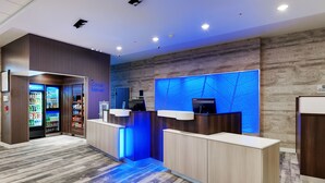Un espace d’accueil comprenant un distributeur automatique, un mur éclairé en bleu et un comptoir.