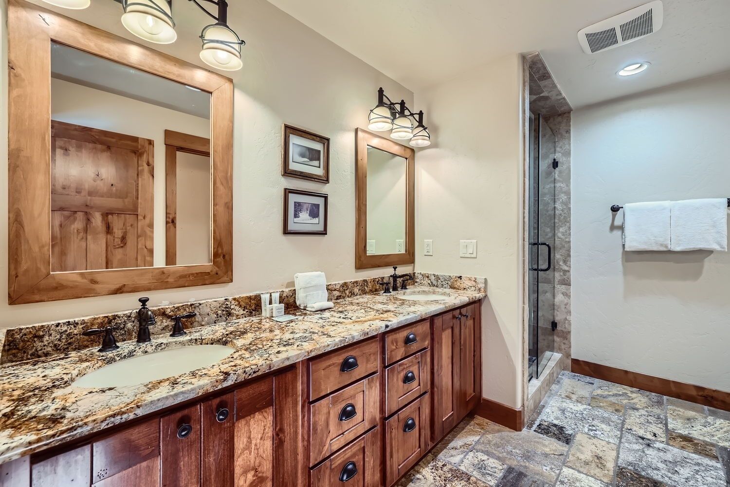 A bathroom with a double sink vanity, wooden cabinets, and a large mirror.