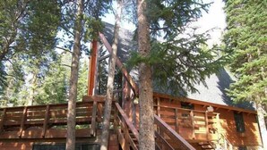 A cabin with a wooden exterior, a staircase, and a window.