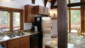A kitchen with wooden cabinets, a granite countertop, a refrigerator, and a dishwasher.