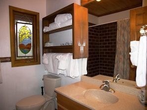 Ein Badezimmer mit Toilette, Waschbecken und einem Buntglasfenster.