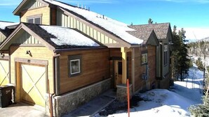 Ein zweigeschossiges Holzhaus mit Steinunterbau, Garage und schneebedecktem Dach.