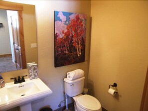 Une salle de bain avec un lavabo, des toilettes et un tableau accroché au mur.