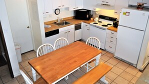 A compact kitchen with white cabinets, a wooden table, and a refrigerator. - Snowflake 1 Bed plus Den 2 Bath (Copper Mountain)