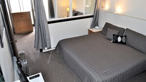A bedroom with a large bed, a dresser, a bedside table, and a window with curtains. - Snowflake 1 Bed plus Den 2 Bath (Copper Mountain)