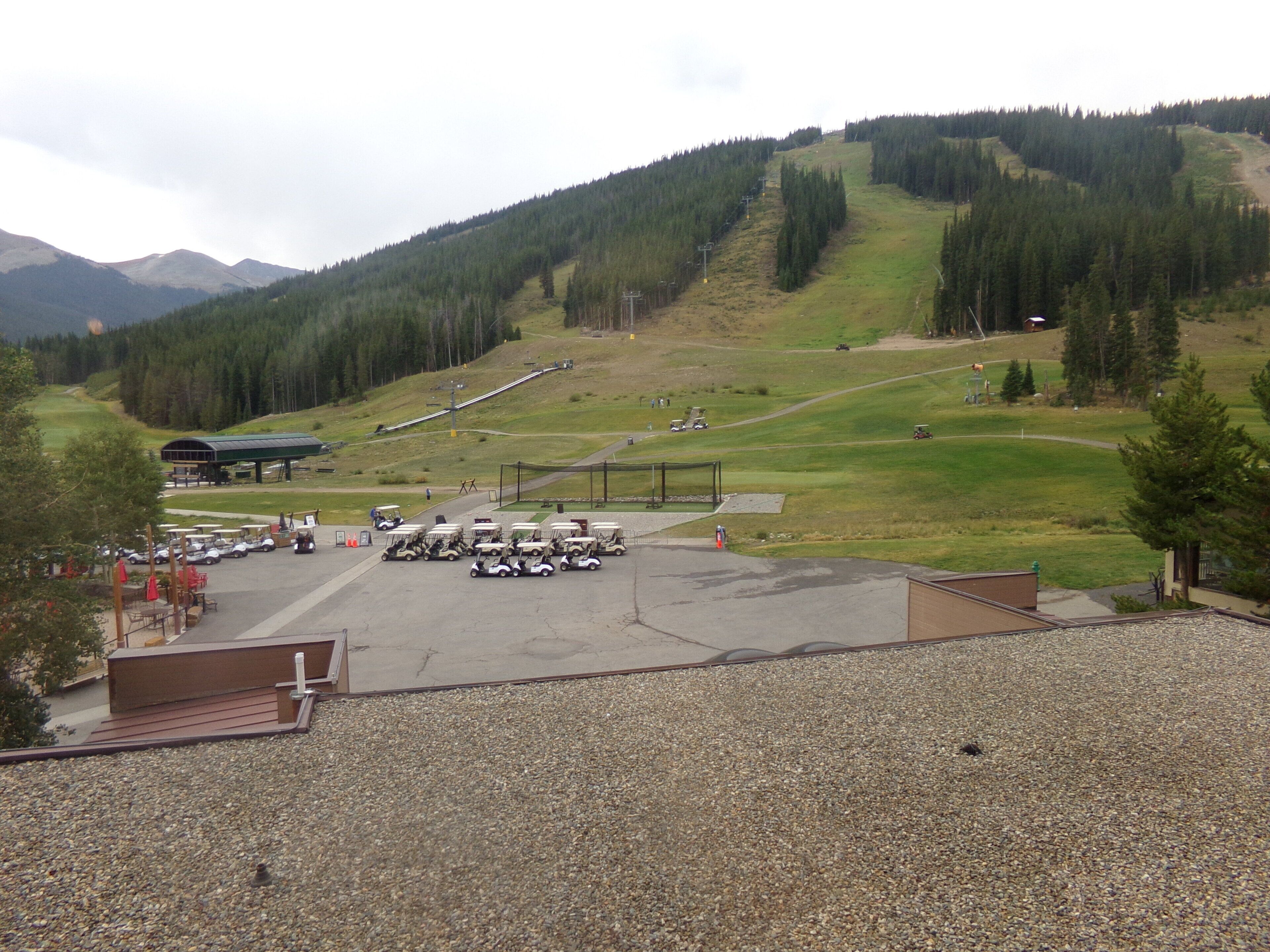 A parking area with golf carts and a covered seating area.
