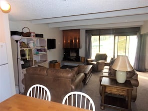 A living room with a fireplace, leather sofa, wooden coffee table, and a dining area with a table and chairs. - Snowflake 1 Bed plus Den 2 Bath (Copper Mountain)