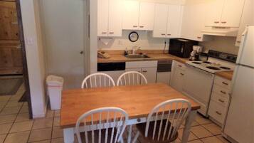 A compact kitchen with white cabinets, a wooden table, and chairs.